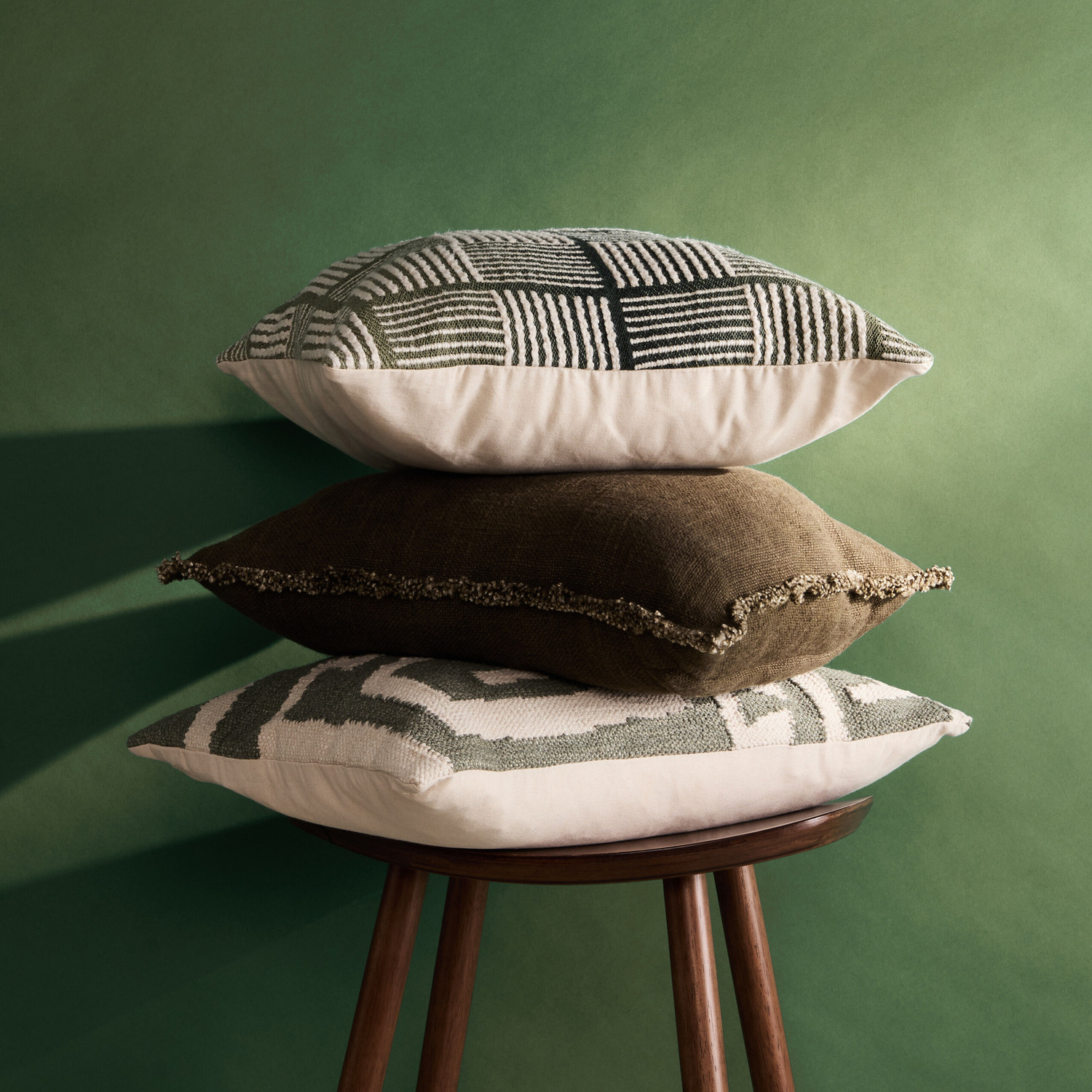 A moody set of cushions against a green background